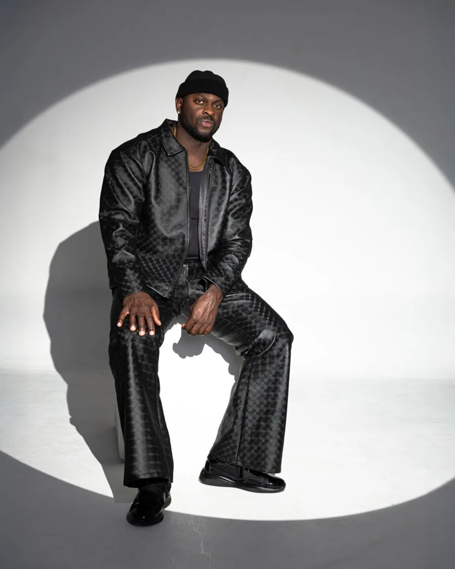 Black leather jacket and monogram trouser, seated